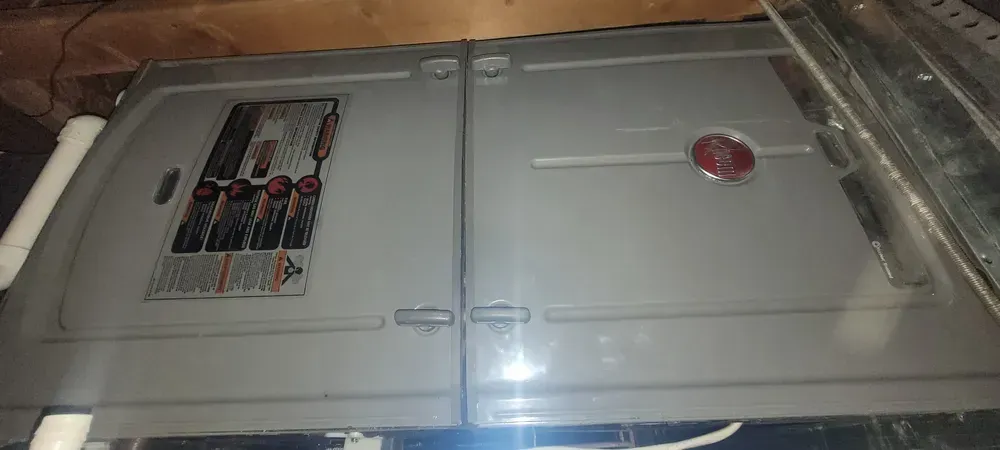 A gray appliance with an information panel and red button; presumably HVAC equipment.