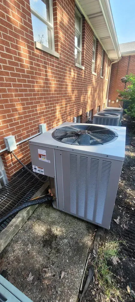 Air conditioning units lined up next to a brick building.
