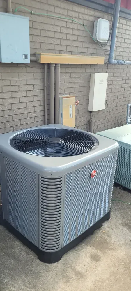 Gray air conditioning unit outside a brick building.