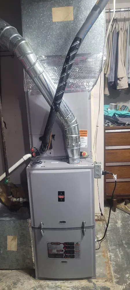 A gray furnace with ductwork in a basement setting.
