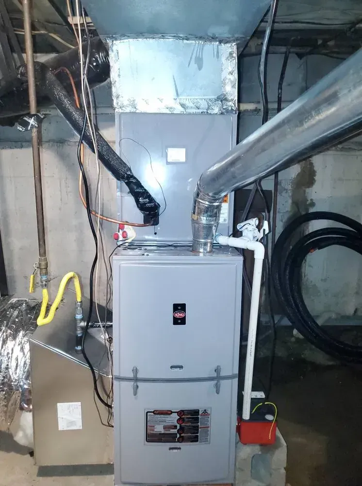 Furnace in a basement, gray metal with ductwork, vents, pipes, and electrical wiring.