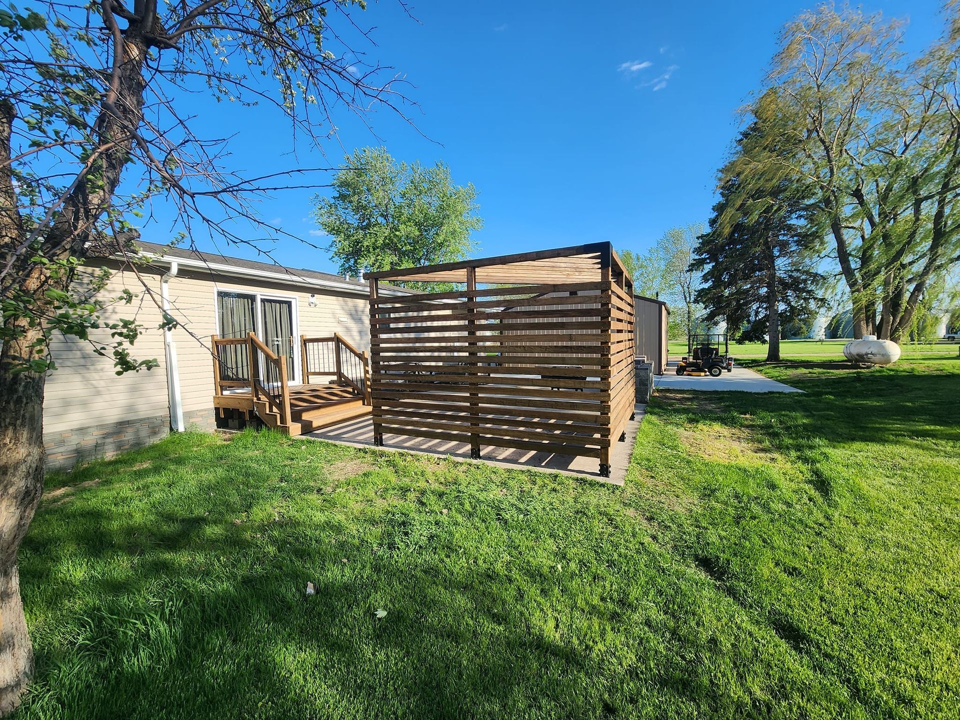 A mobile home with a wooden gazebo in the backyard.