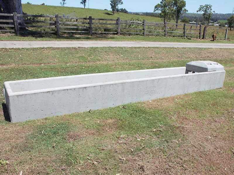A Concrete Block Trough in A Grassy Field — Hazells Farm & Fertilizer Services in Taminda, NSW