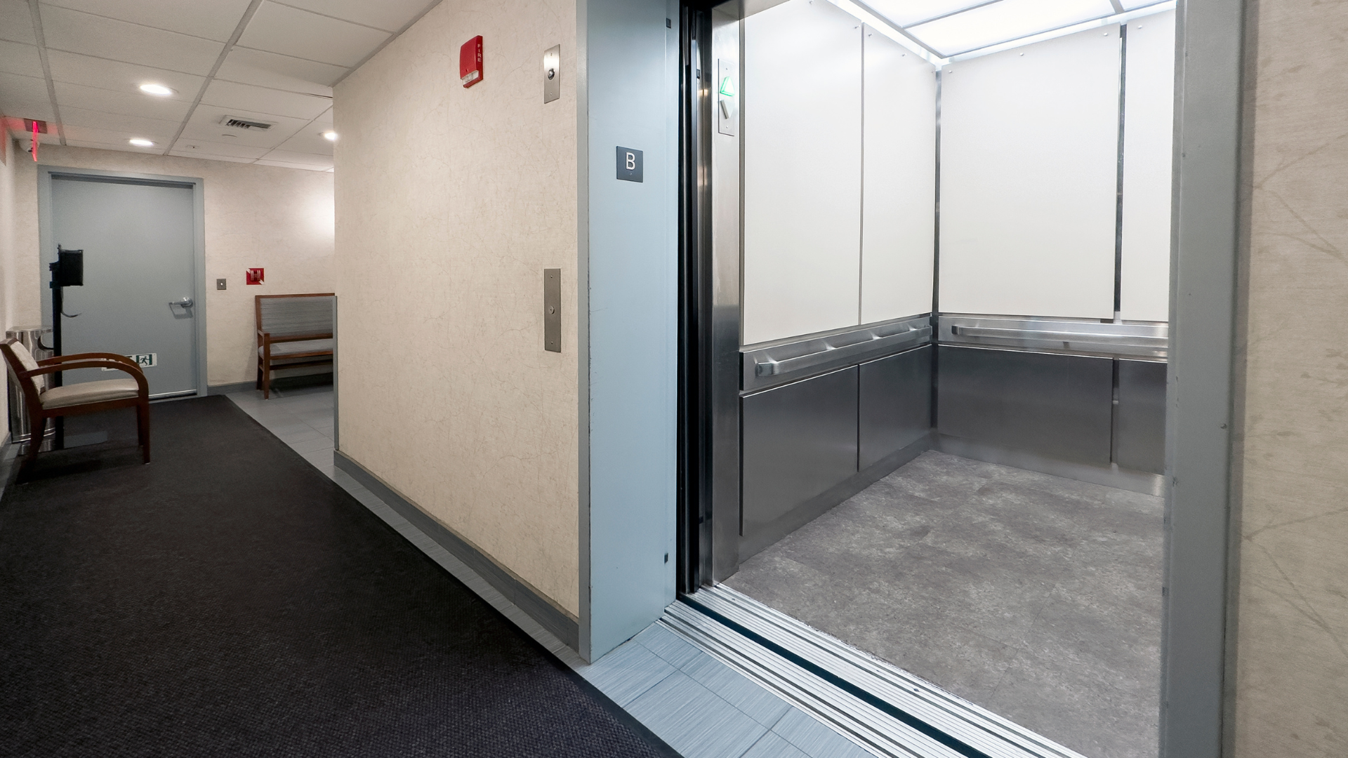An elevator is sitting in a hallway with the door open.
