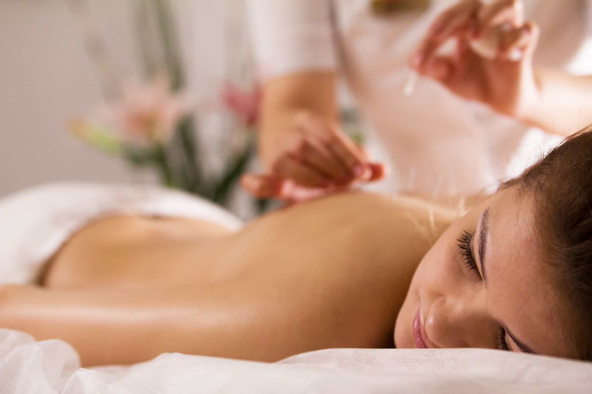 A woman is getting acupuncture on her back in a spa.