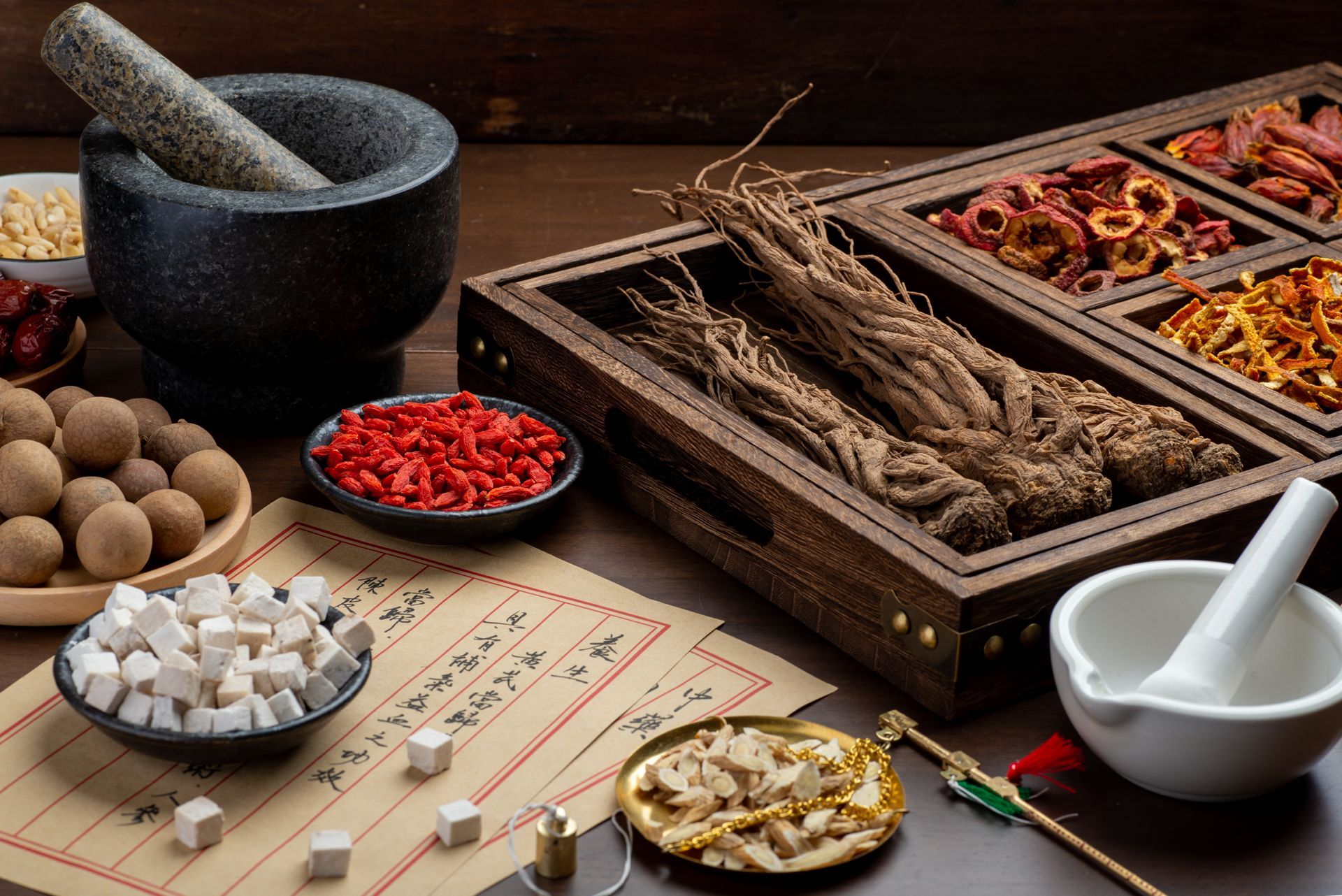 A mortar and pestle surrounded by bowls of chinese herbs on a table.