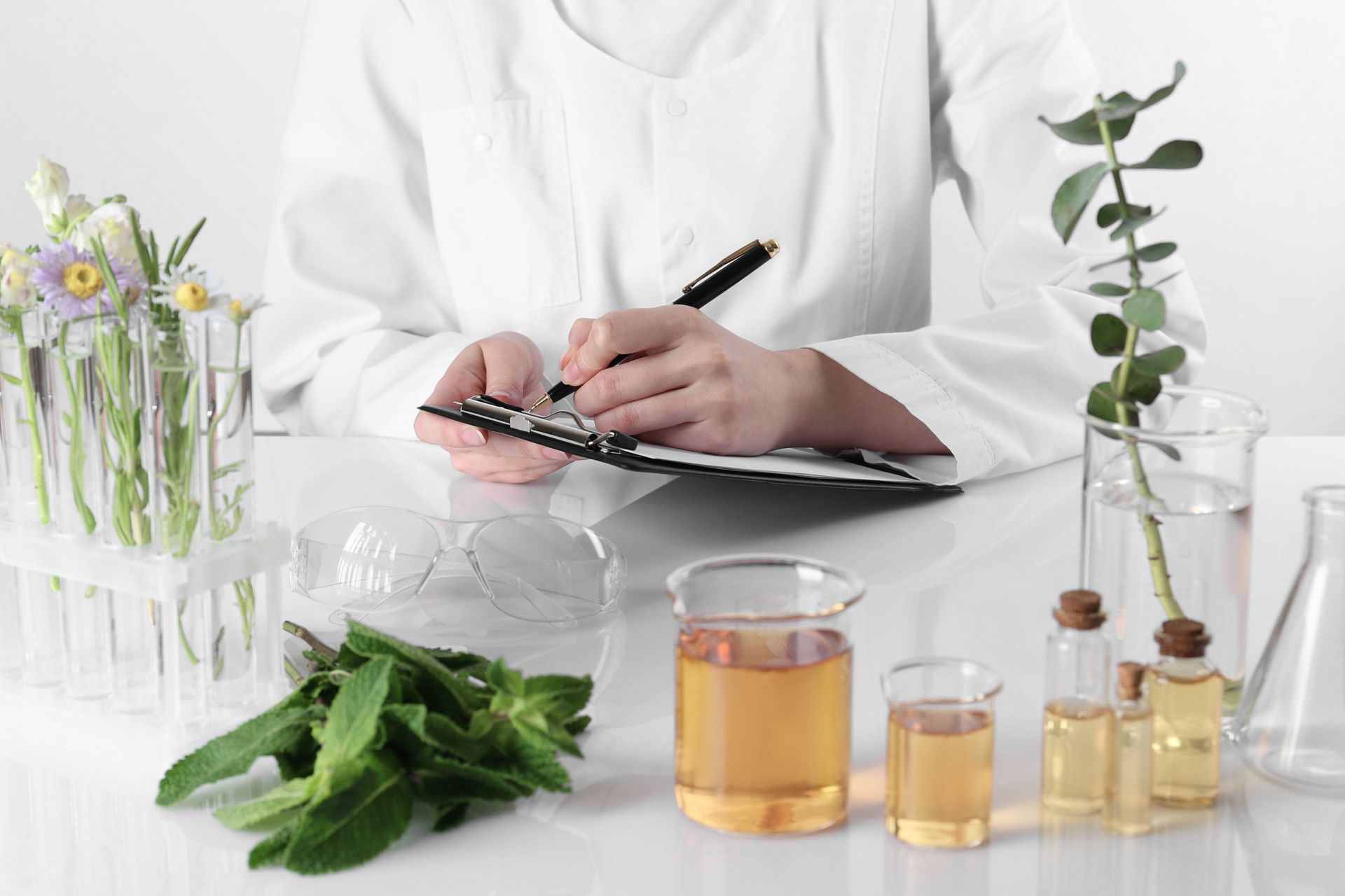 A scientist is sitting at a table with a clipboard and a pen.