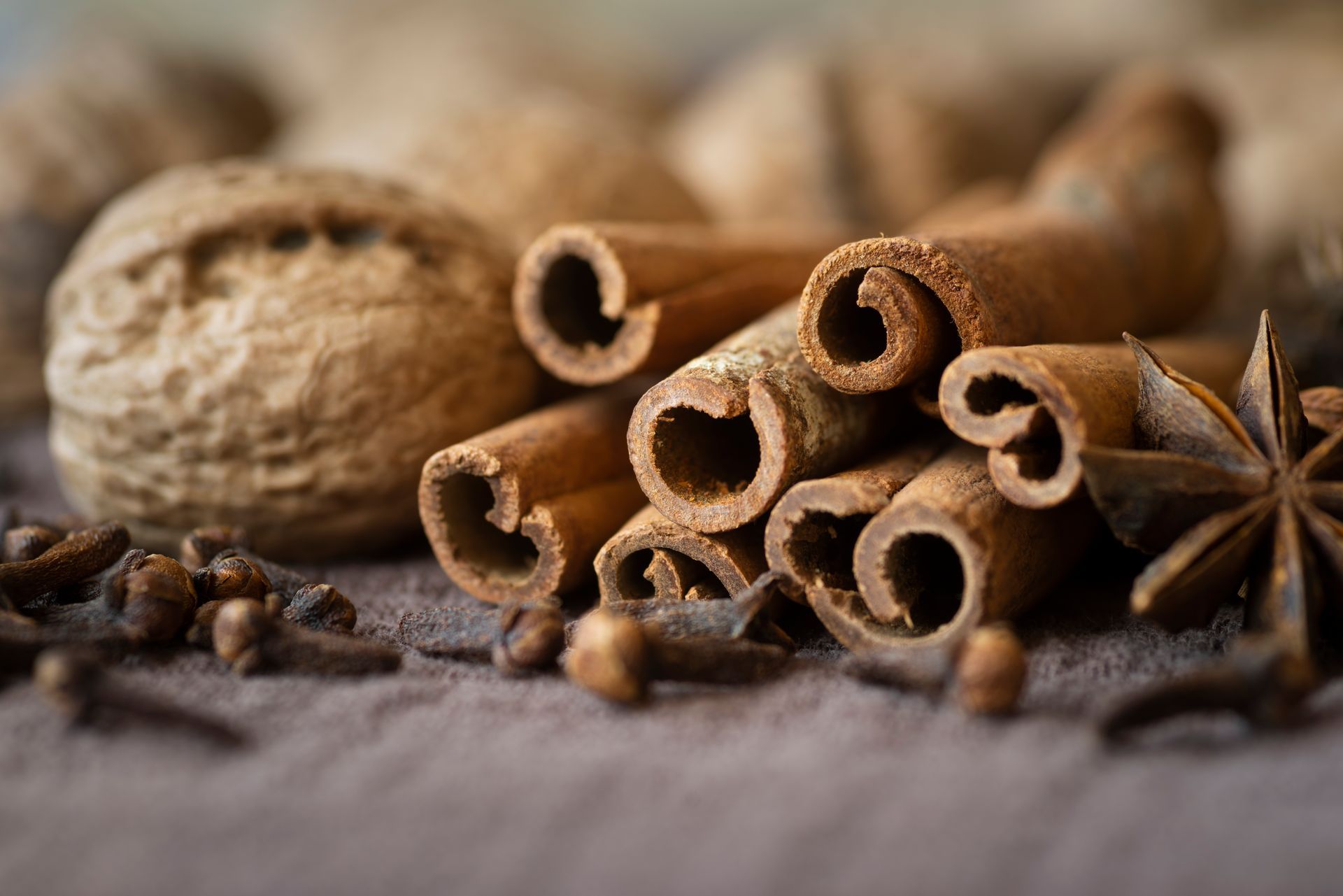 A pile of cinnamon sticks , star anise , nutmeg and cloves on a table.
