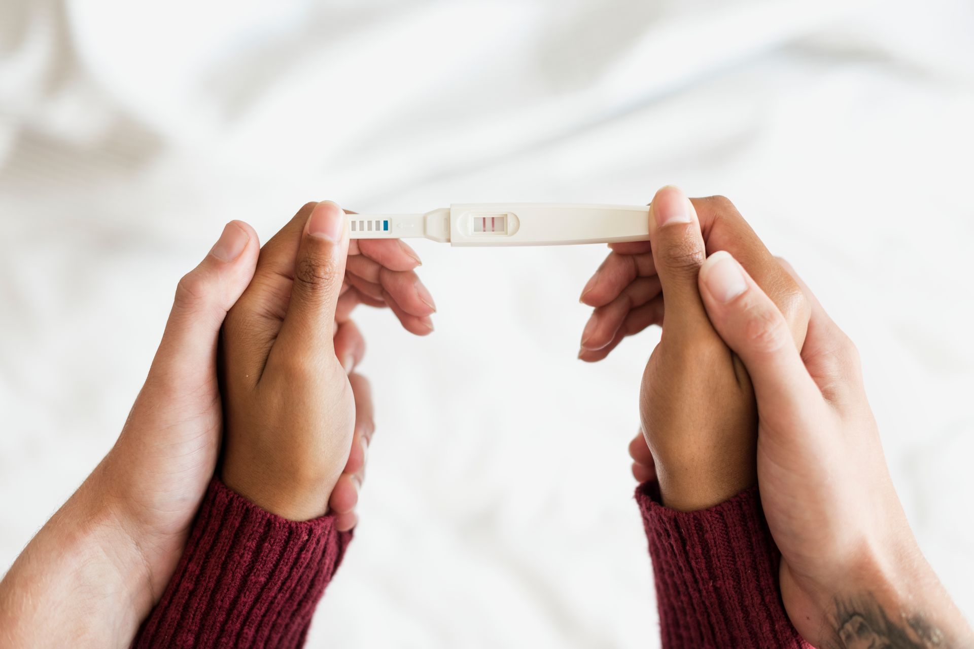 A man and a woman are holding hands and looking at a pregnancy test.
