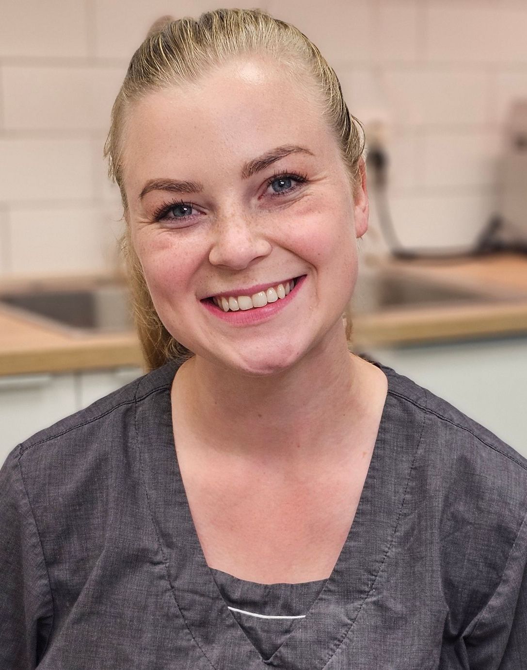 En kvinne med langt blondt hår smiler til kameraet.