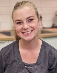 En kvinne med langt blondt hår smiler til kameraet.