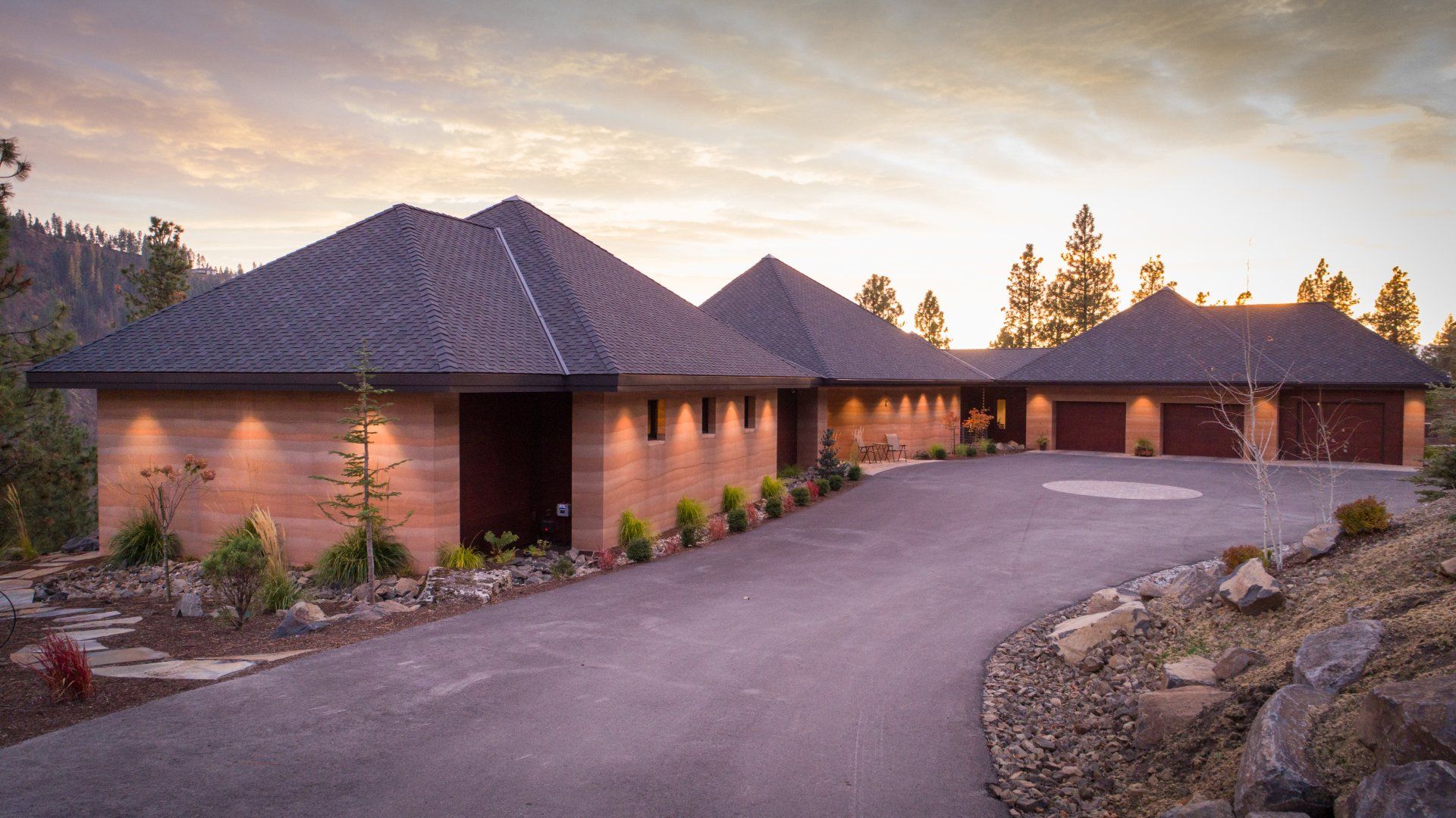 modern rammed earth house with 3 car garage at twilight