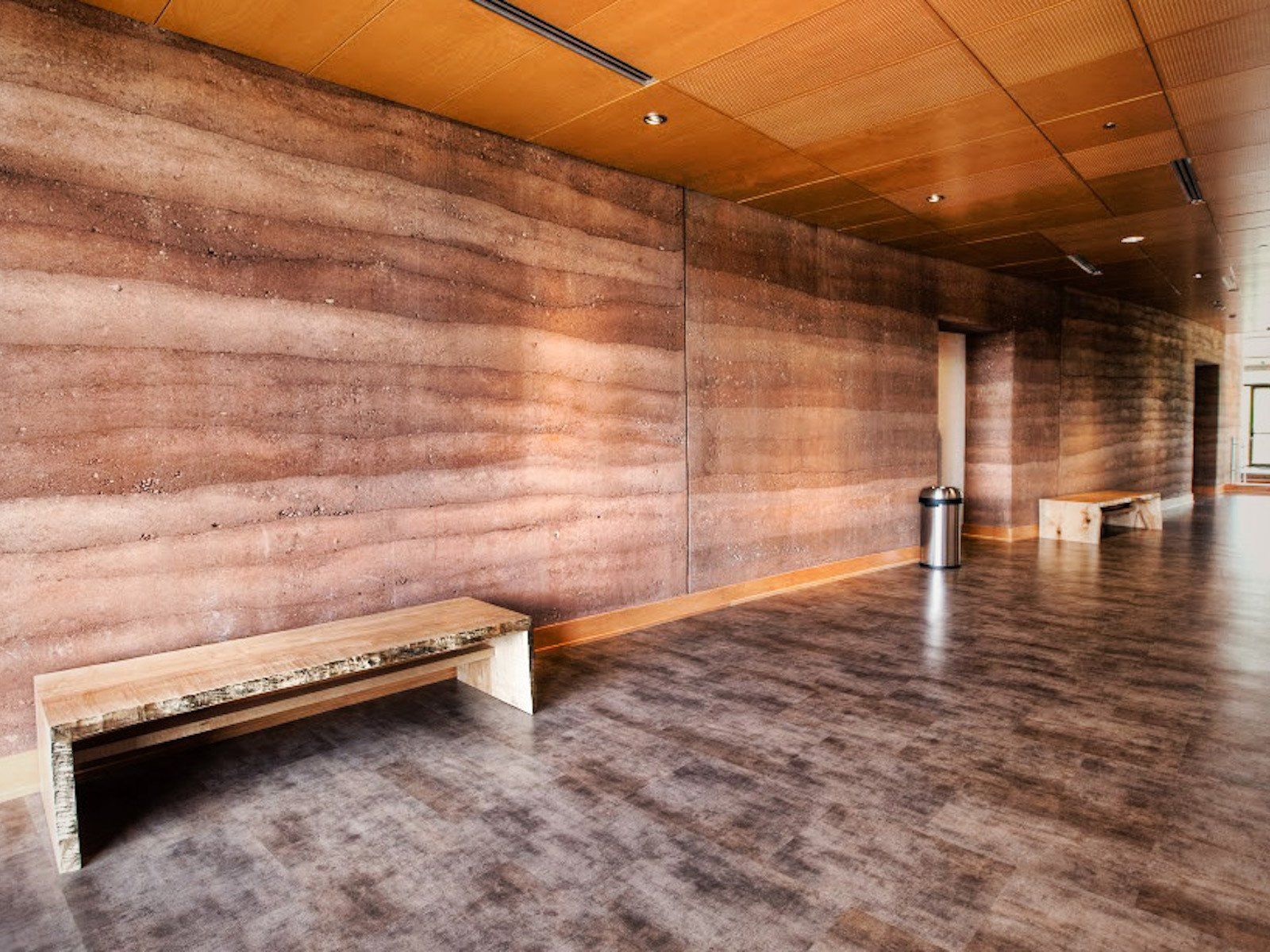 Brinton Museum interior rammed earth wall and floor with seating areas for visitors and a metal trash can