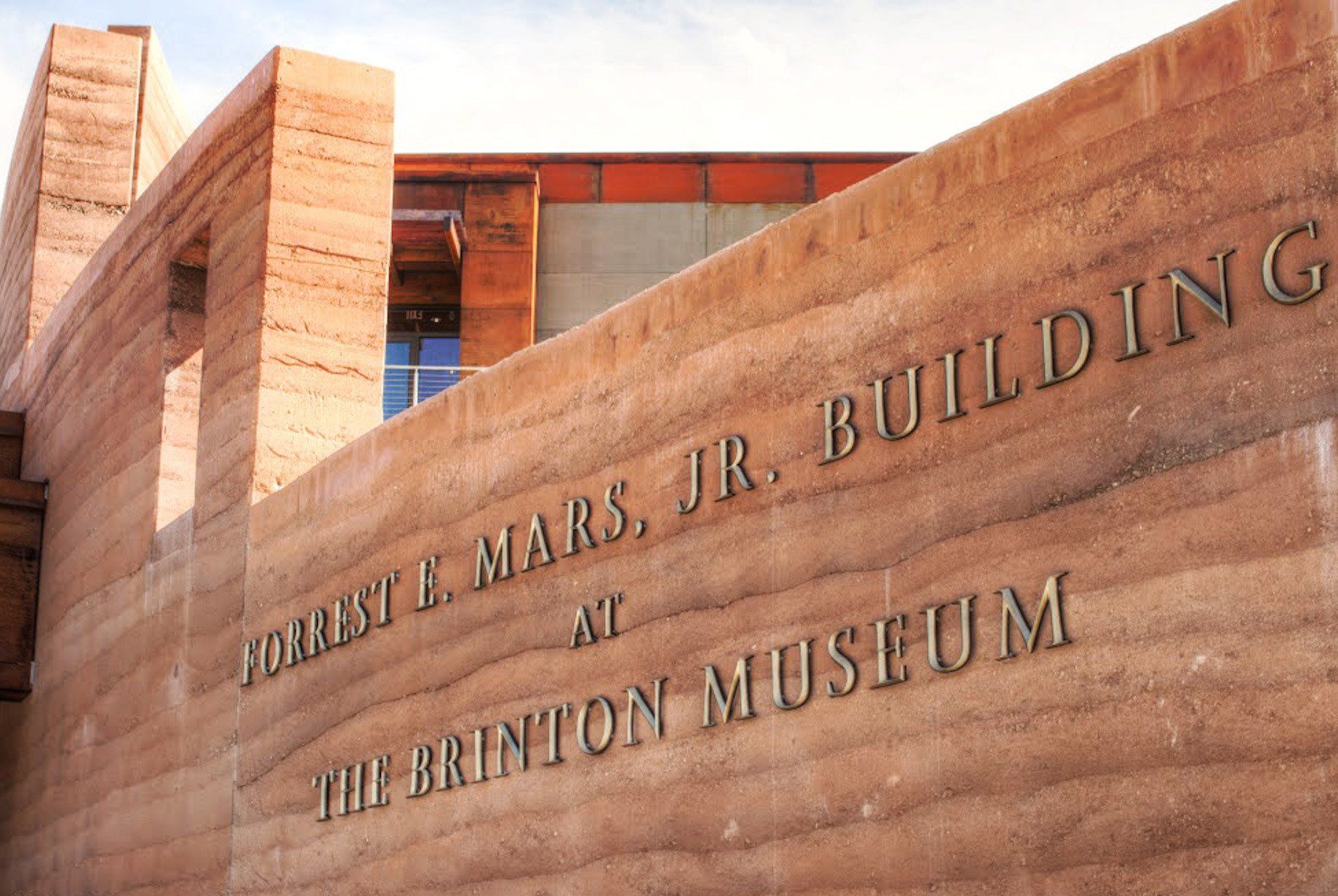 Brinton Museum main entrance sign, gold letters on rammed earth wall