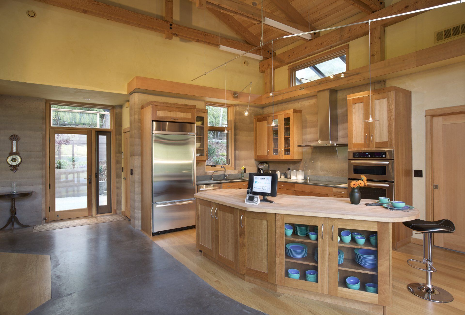 modern kitchen with stainless steel appliances, large island and rammed earth SIREWALLs