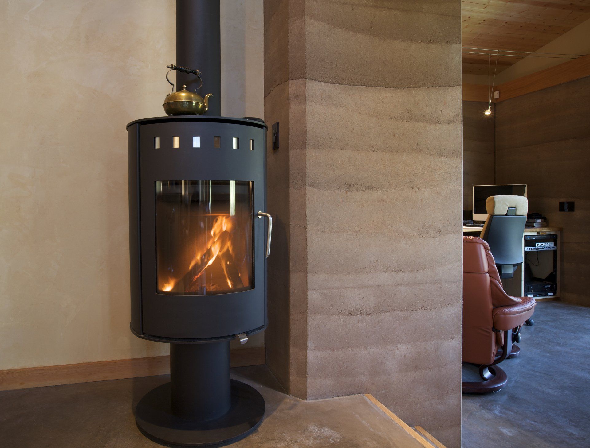 small woodburning stove next to rammed earth wall