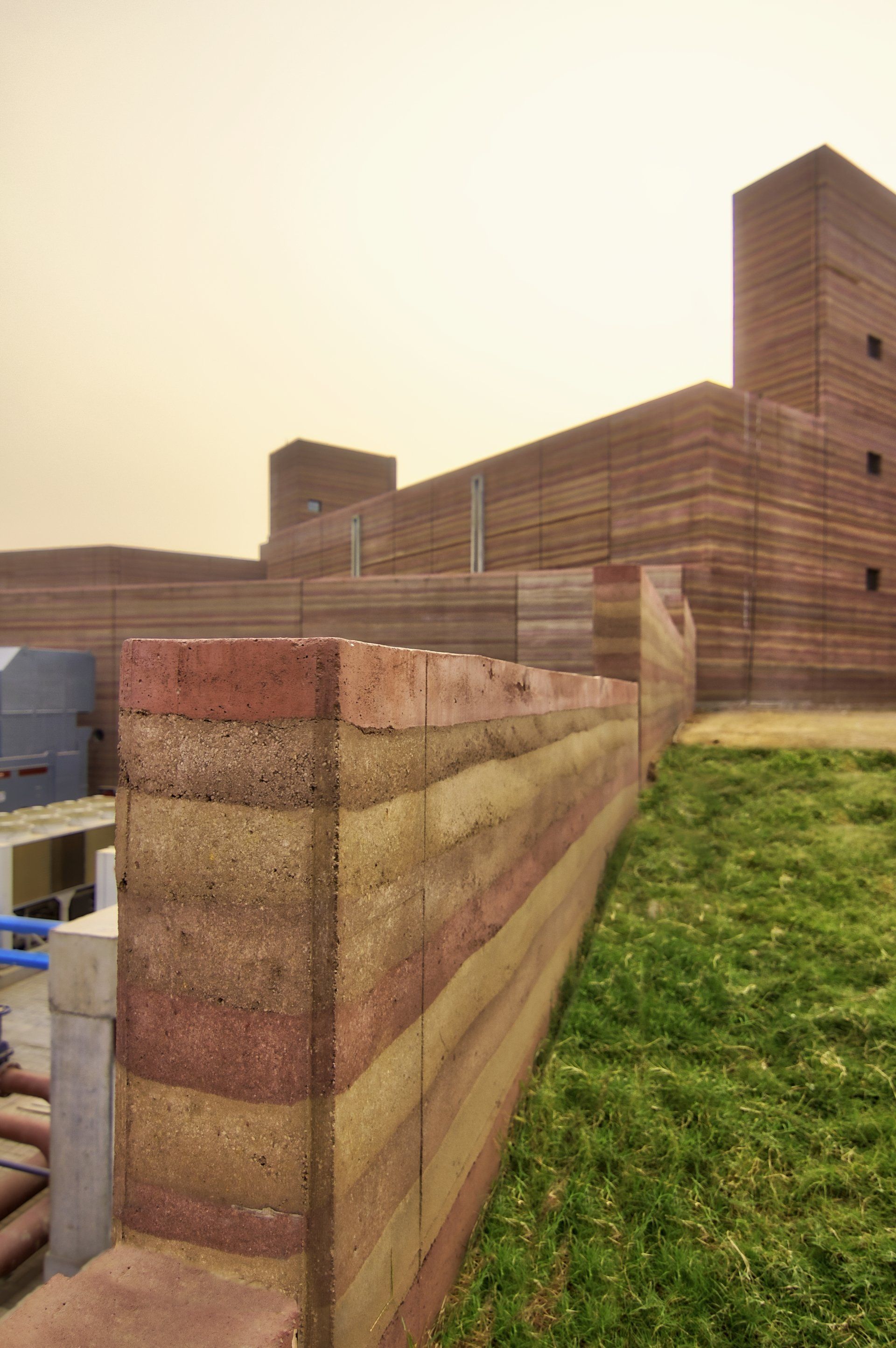 rammed earth SIREWALL close up with commercial office building behind it