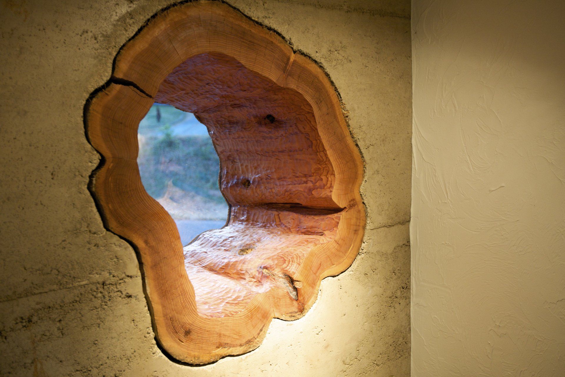 window made out of a hollow tree stump surrounded by rammed earth walls
