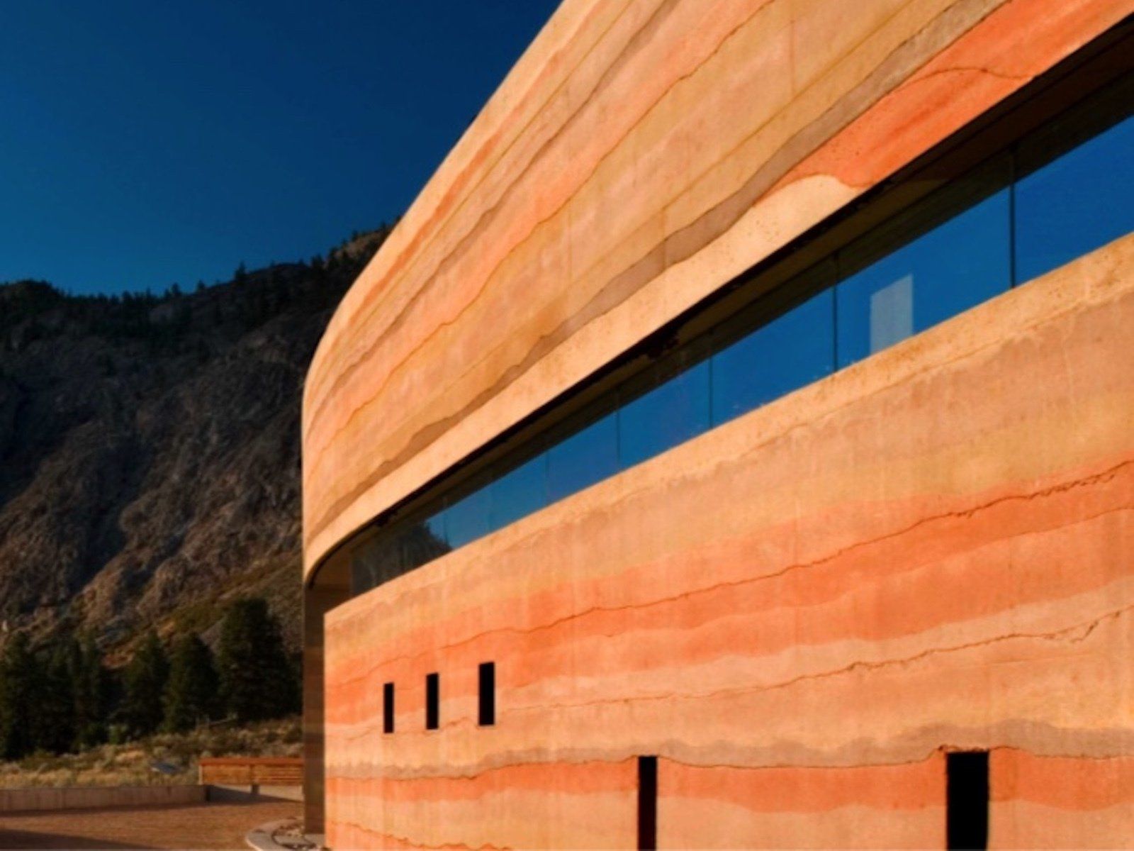 nk mip side view of curving rammed earth wall in various colors with horizontal window opening