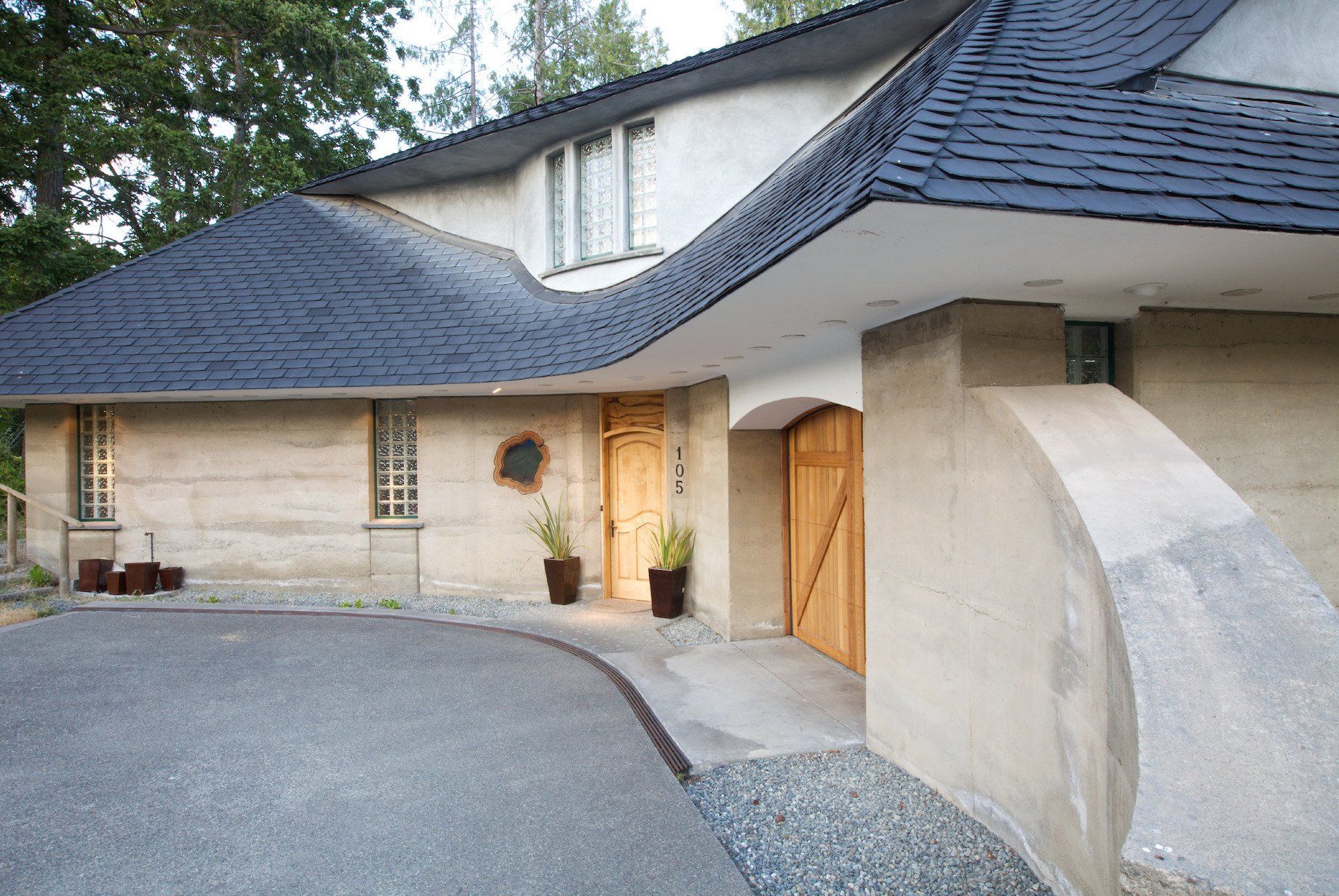 Meror and mikes house exterior side view of front with curving, two story roof lines and light wood front door