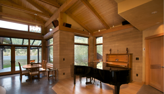 rammed earth home with tall ceilings and a piano