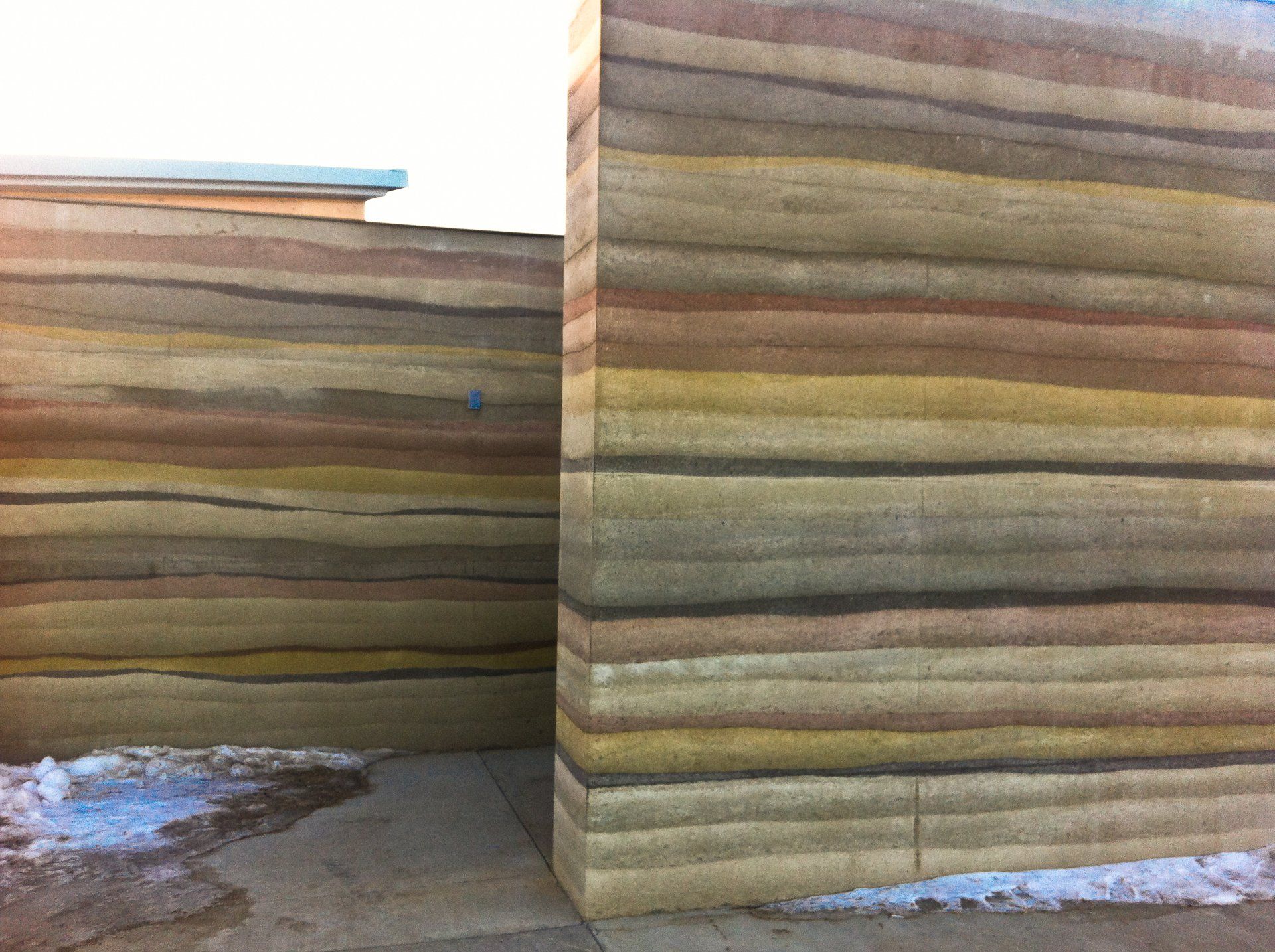 two thick, brightly colored rammed earth walls