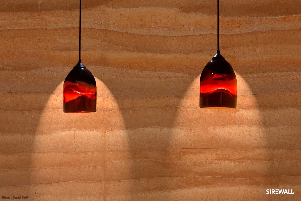 wo red glass pendant lights shining down on rammed earth SIREWALL