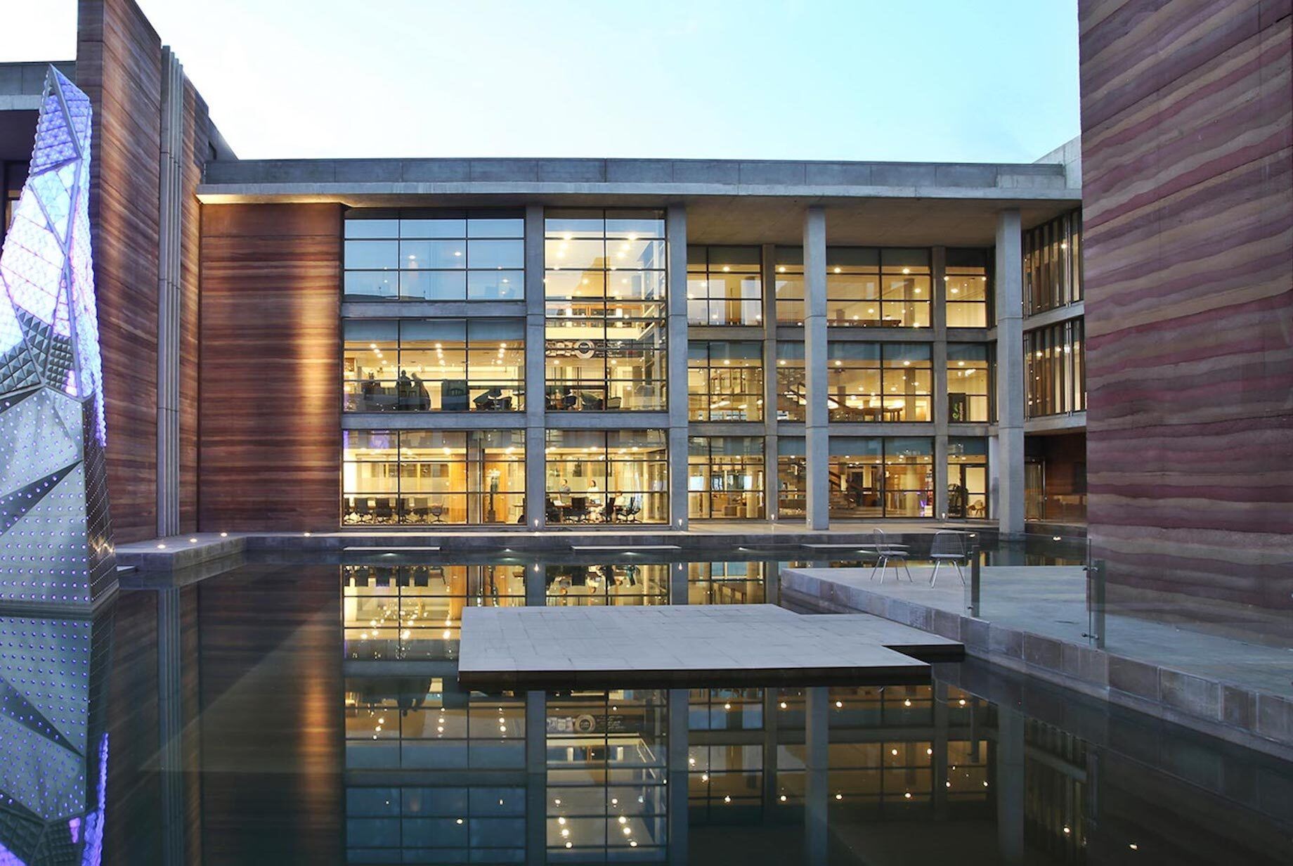 Telenor Arcop illuminated courtyard with building reflected in pond  water