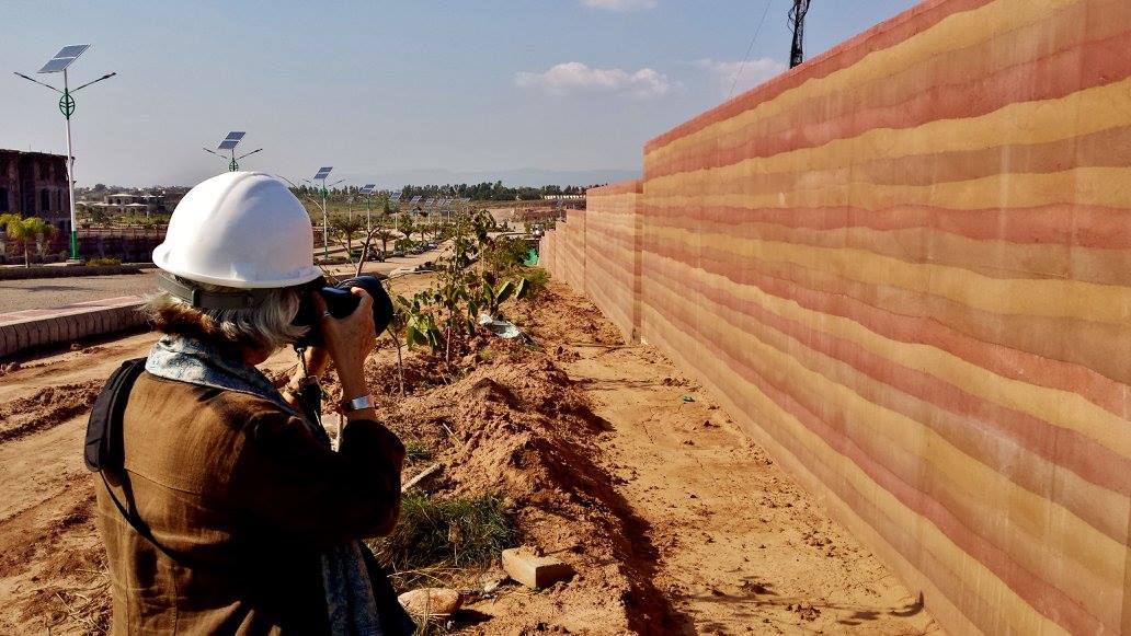 woman with a hard hat and a camera  taking a photo of the longest SIREWALL in the world