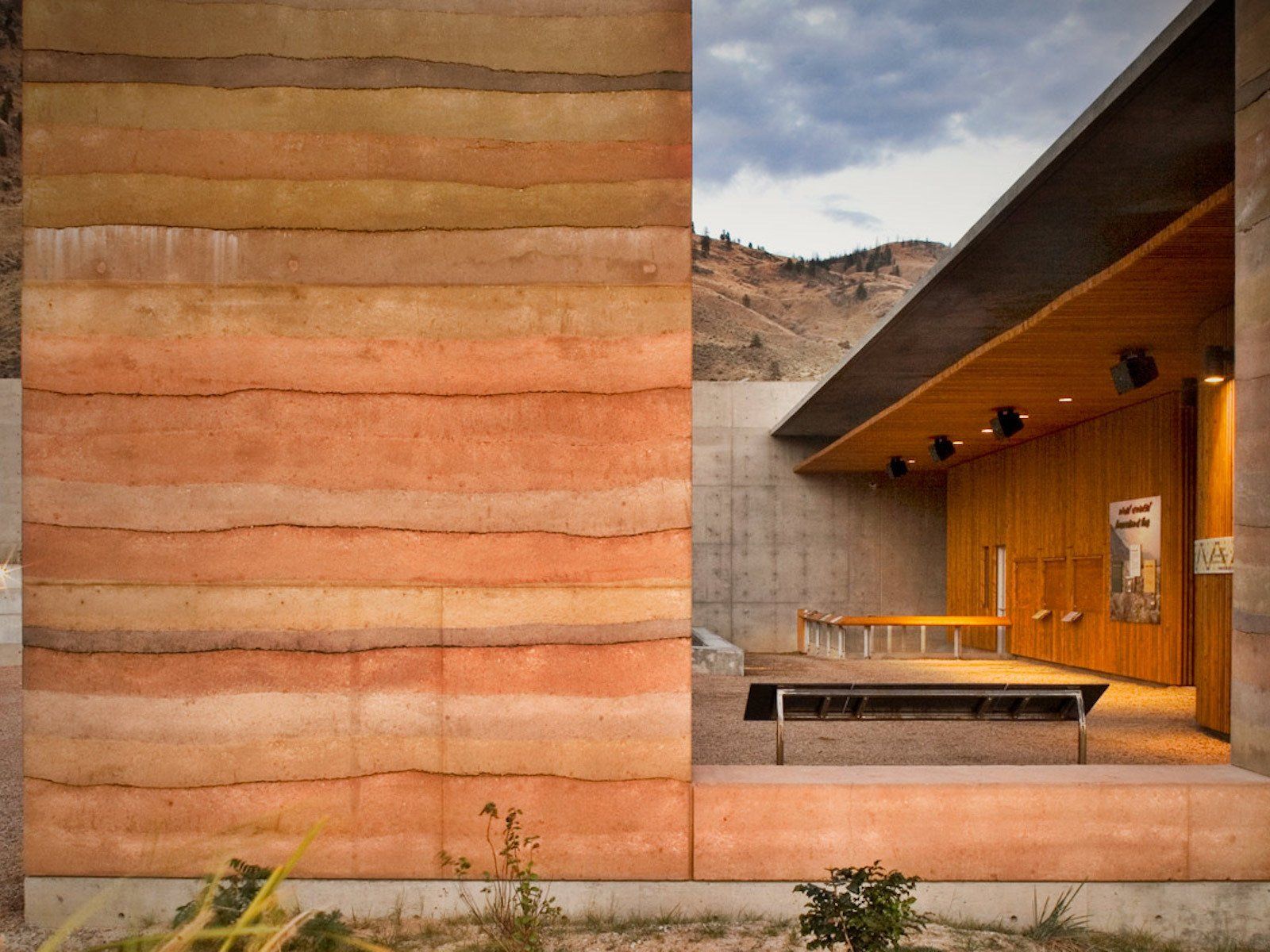 tall rammed earth exterior SIREWALL that frames and exterior patio to the right