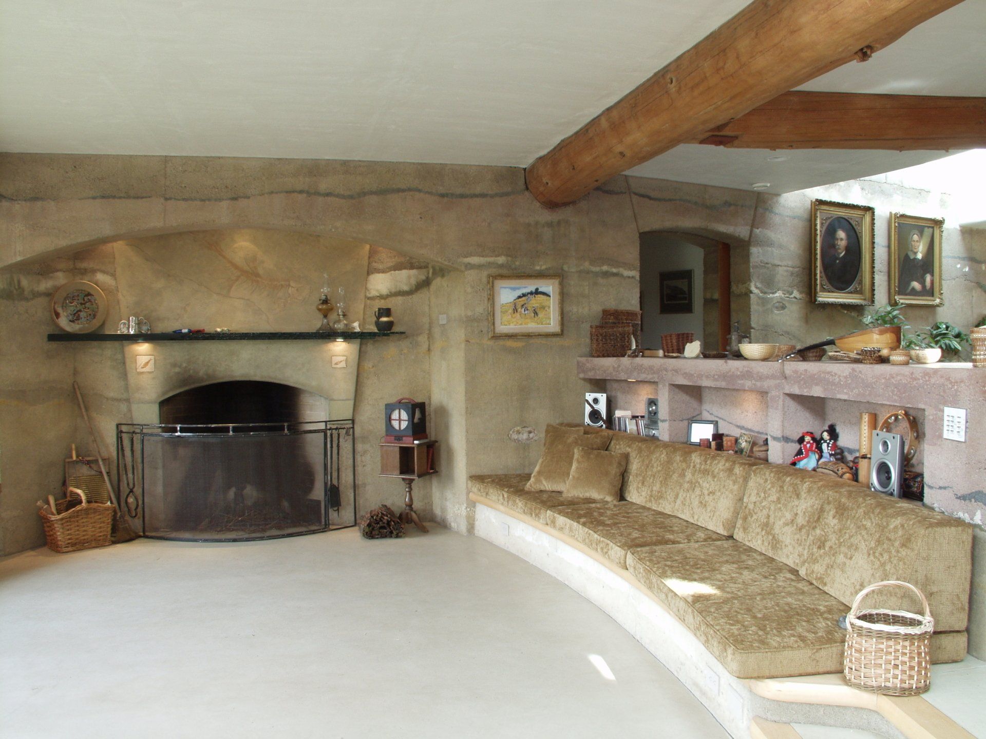 living room with large fireplace, round build-in banco and rammed earth walls