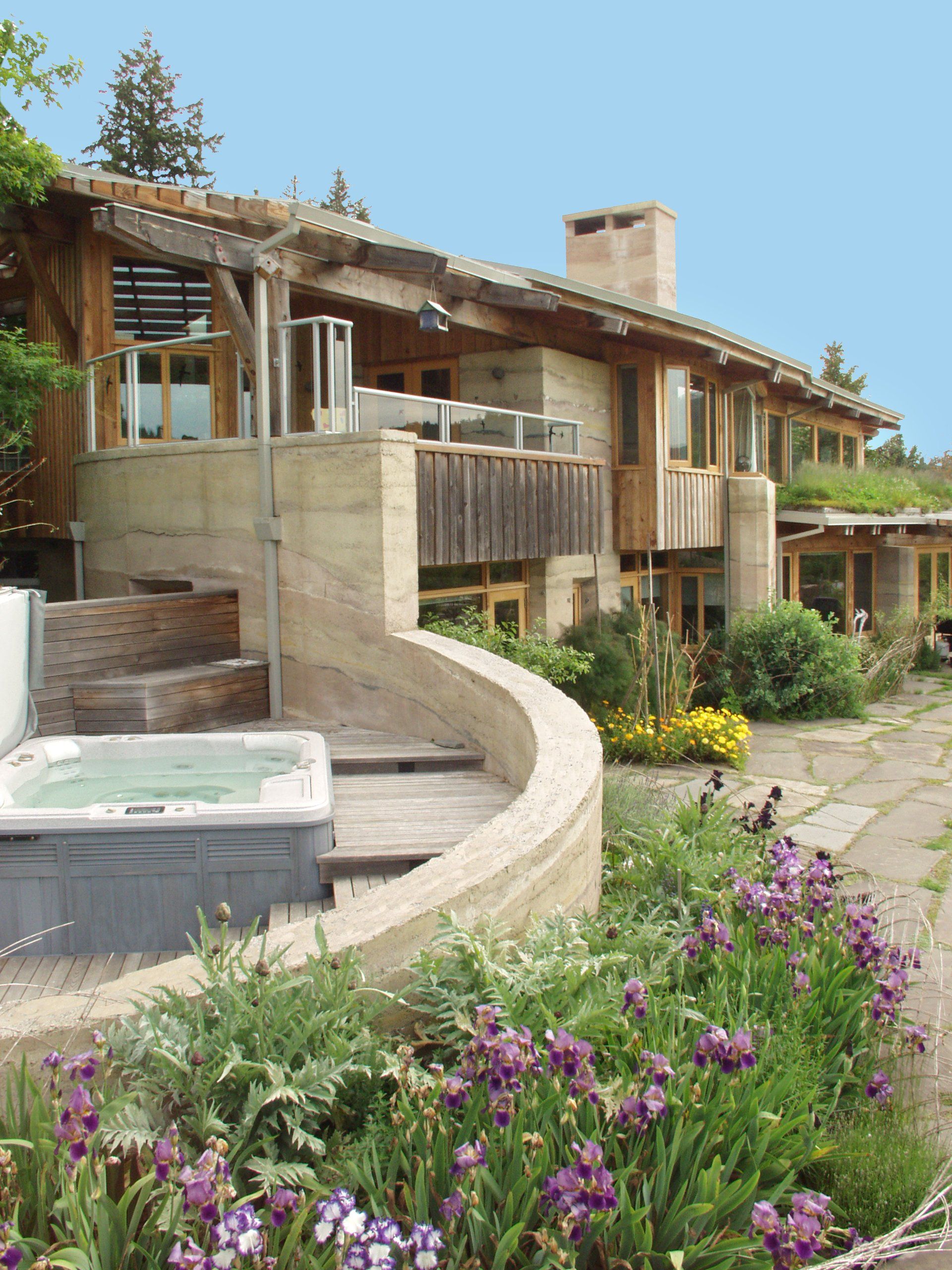two story SIREWALL house with curved rammed earth walls surrounding a hot tub