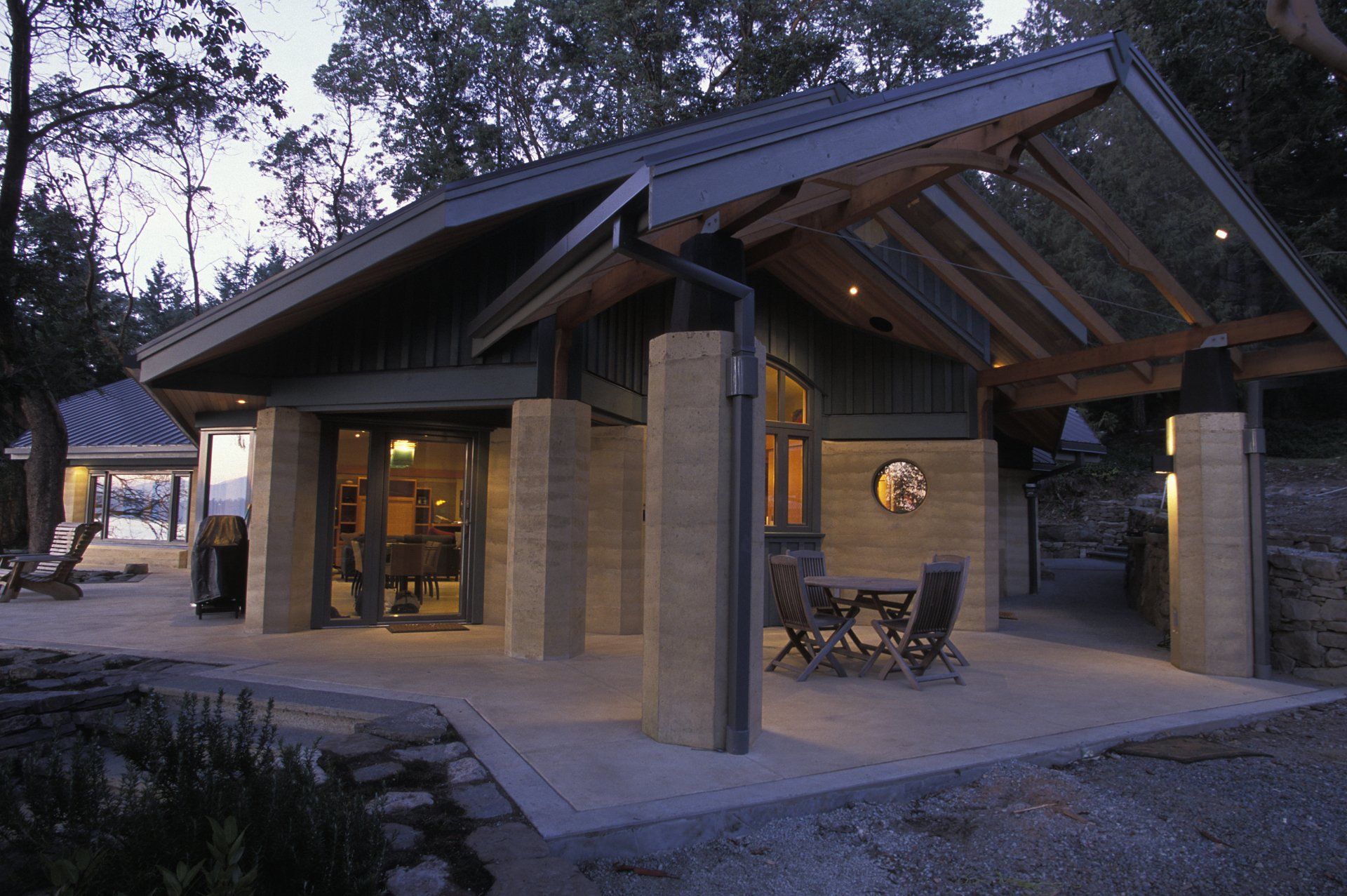 exterior of modern rammed earth home with angular metal roof and large SIREWALL pillars
