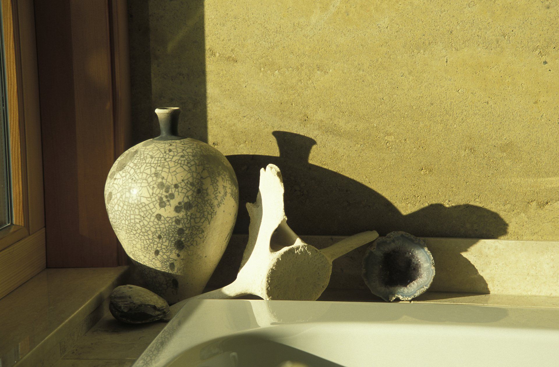 pottery vase and animal bone near a window against SIREWALL rammed earth