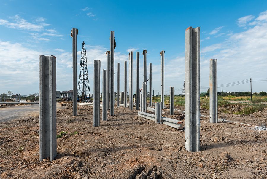 a row of concrete poles are sitting in the dirt on a construction site .