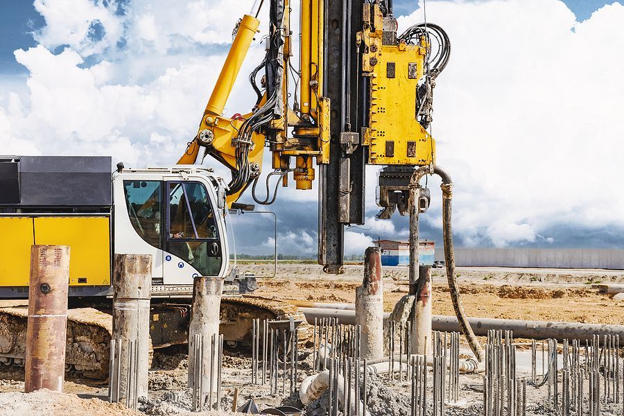A construction site with a yellow excavator and a drill.