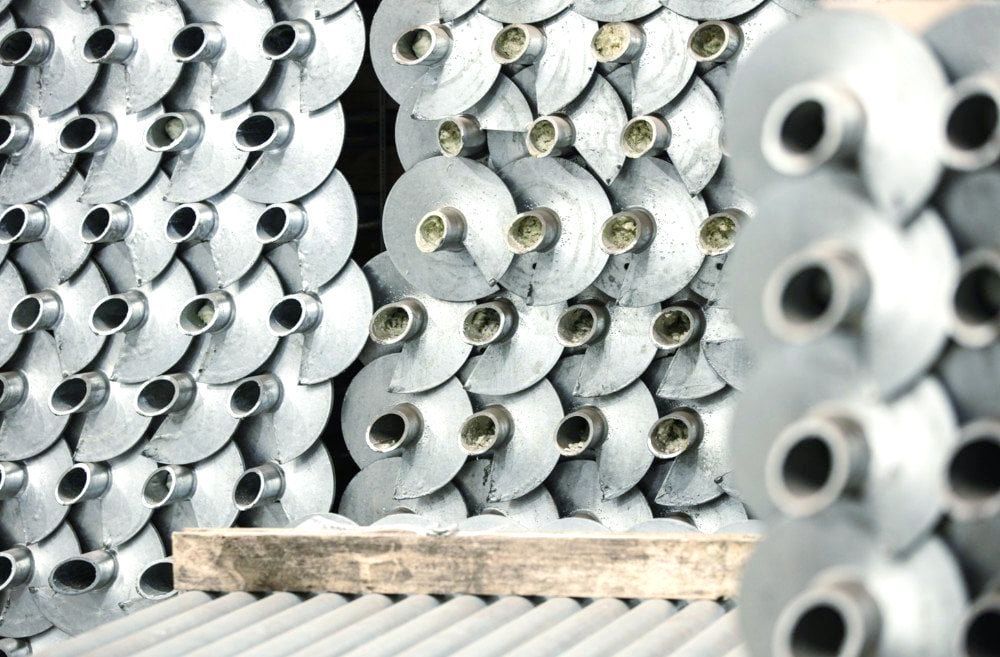 A bunch of metal helical piles are stacked on top of each other.