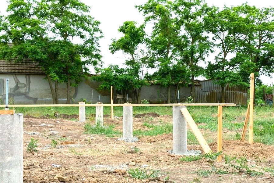 A fence is being built in a field with trees in the background