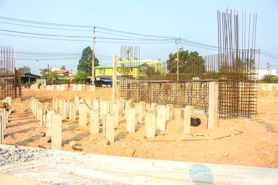 A construction site with a lot of concrete pillars in the dirt.