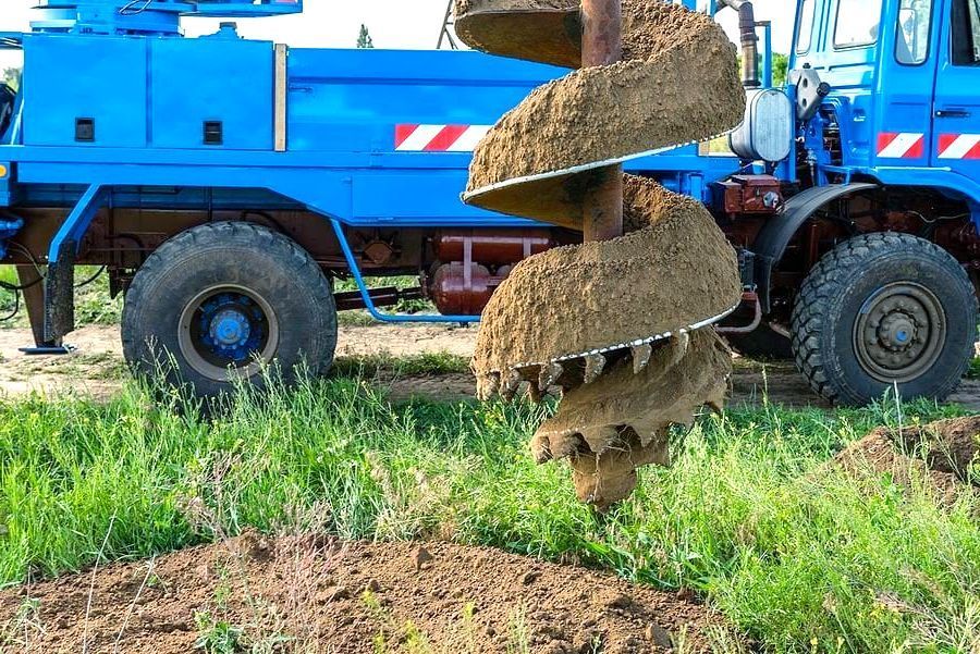 A blue truck is digging a hole in the ground.