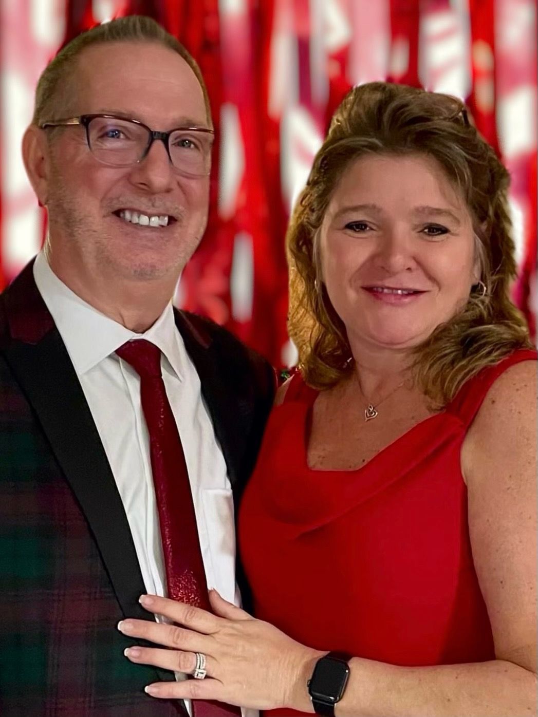 A man in a suit and tie is standing next to a woman in a red dress.