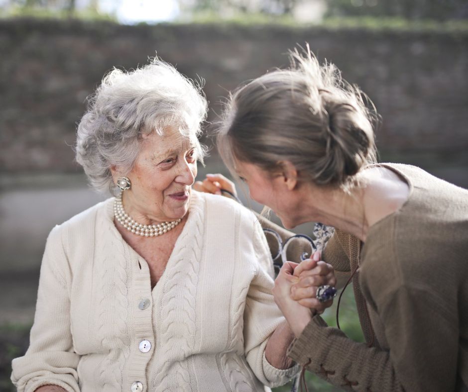 A young woman is holding the hand of an older woman.