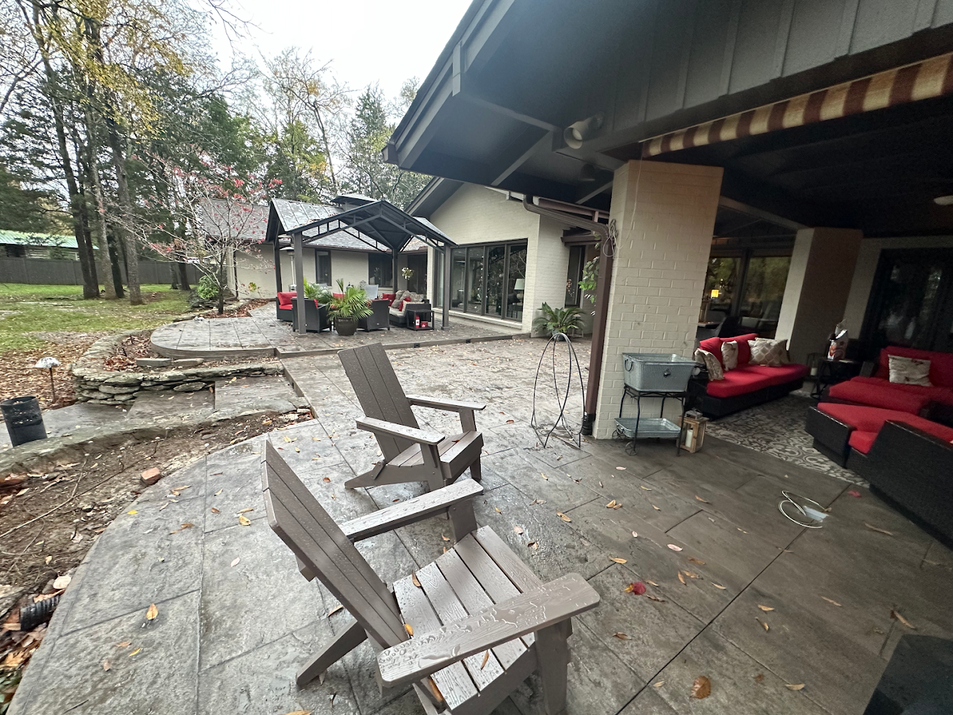A stamped patio with chairs and a couch in front of a house.