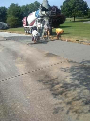 A concrete mixer truck is pouring concrete into a driveway.
