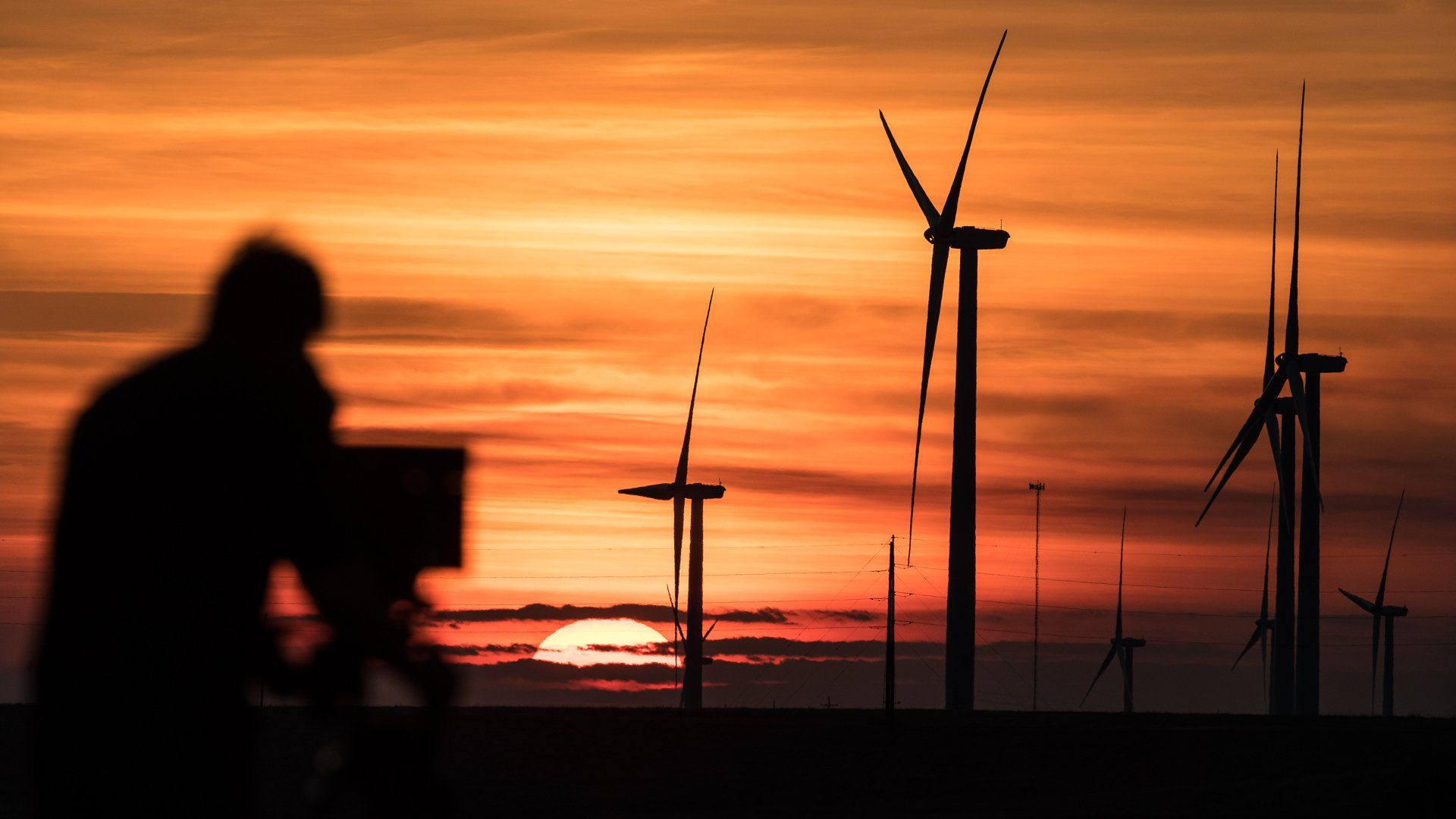 wind turbines with a bright orange sunset in the background