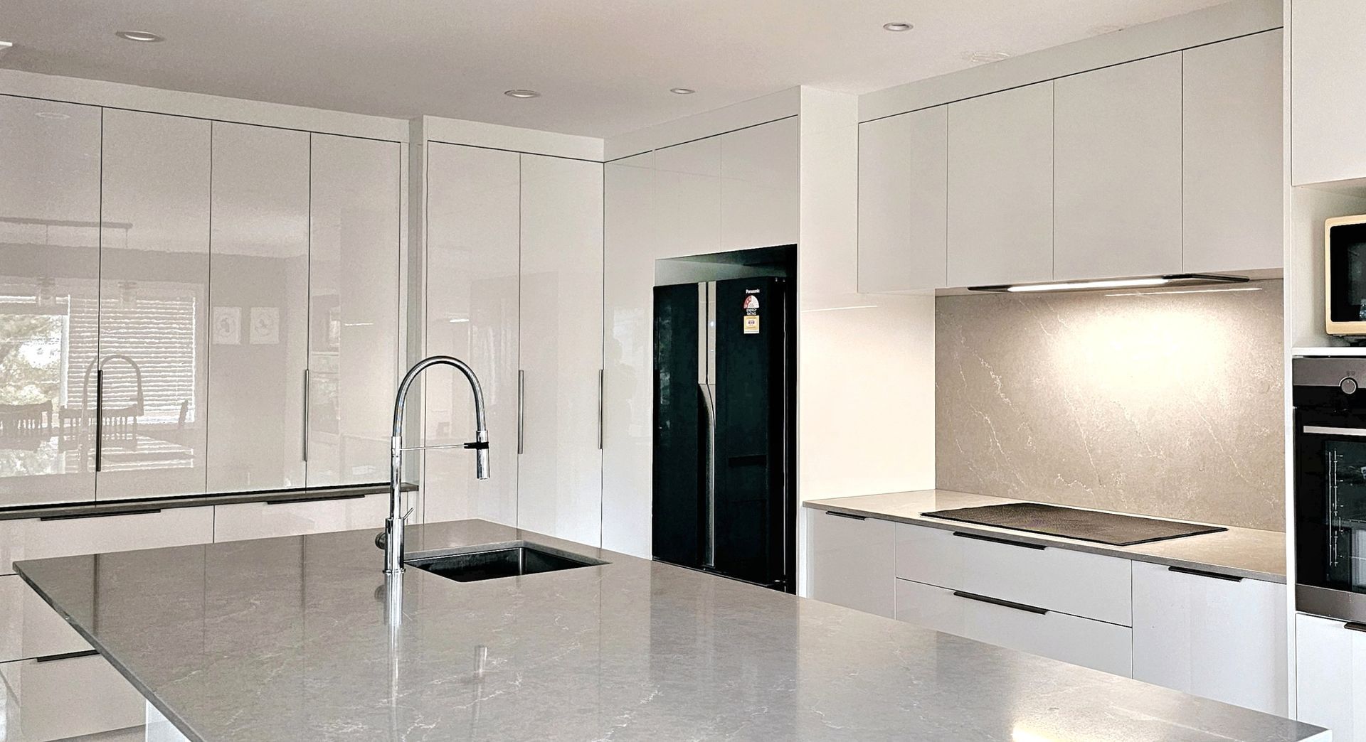 A kitchen with white cabinets and a black refrigerator