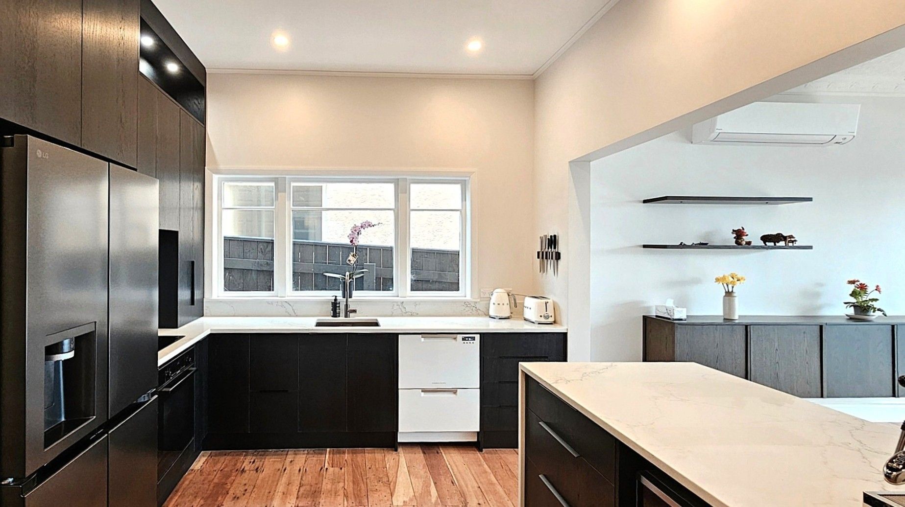 A kitchen with white cabinets , a stainless steel refrigerator , a sink , and a large island.