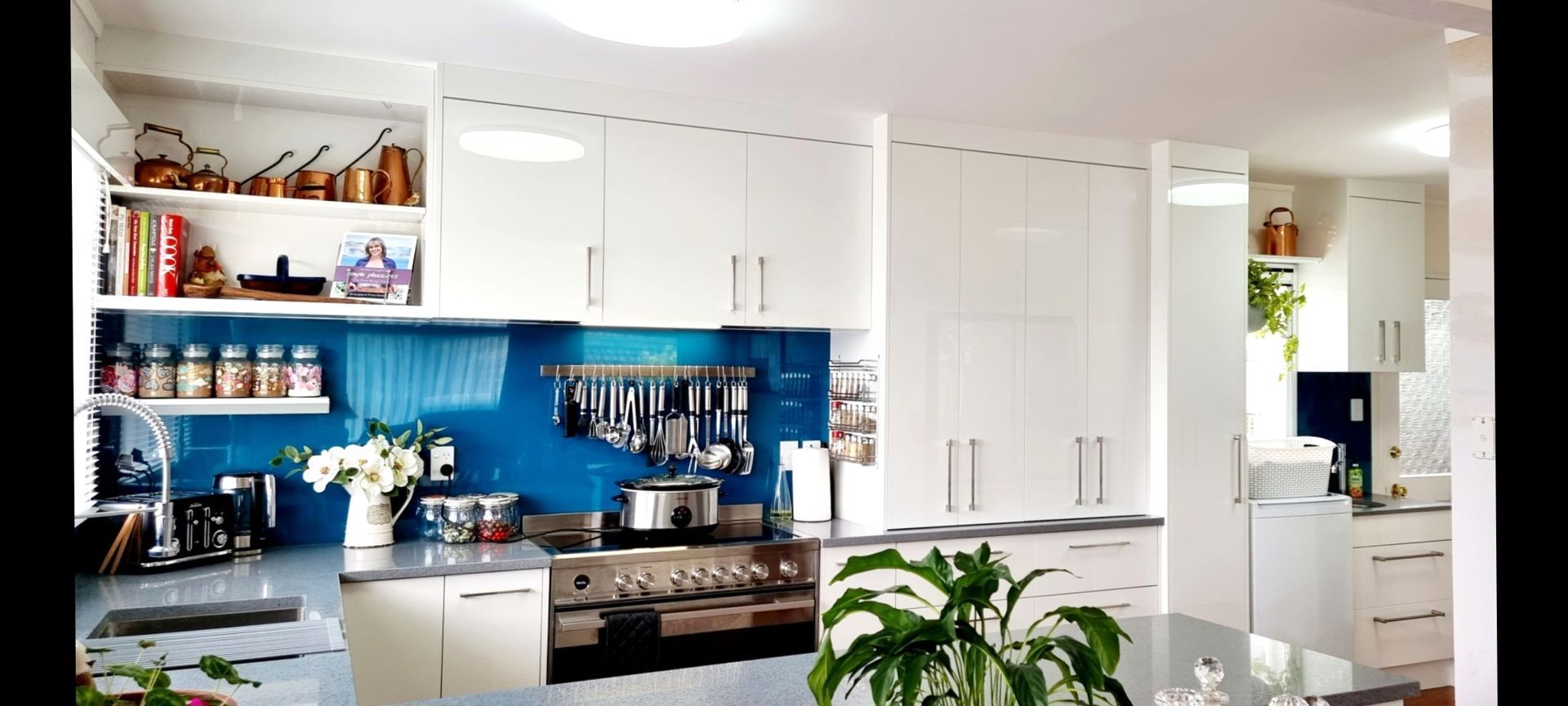 A kitchen with white cabinets and a blue backsplash