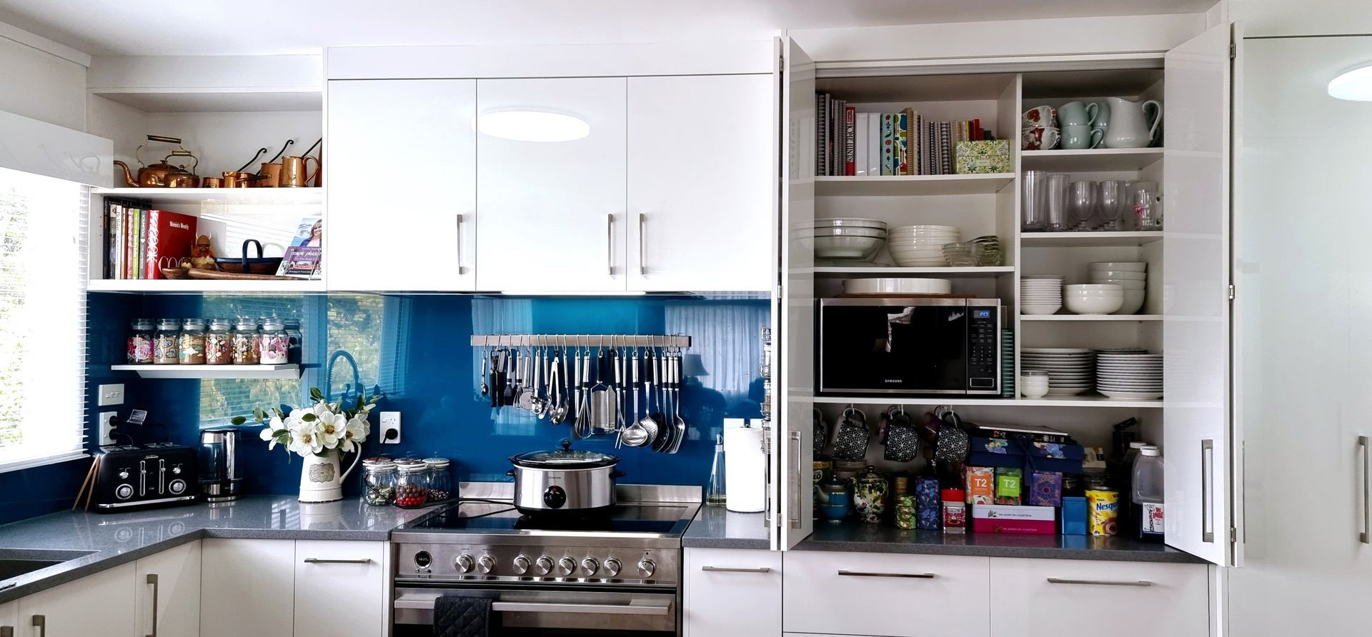 A kitchen with white cabinets and a blue backsplash