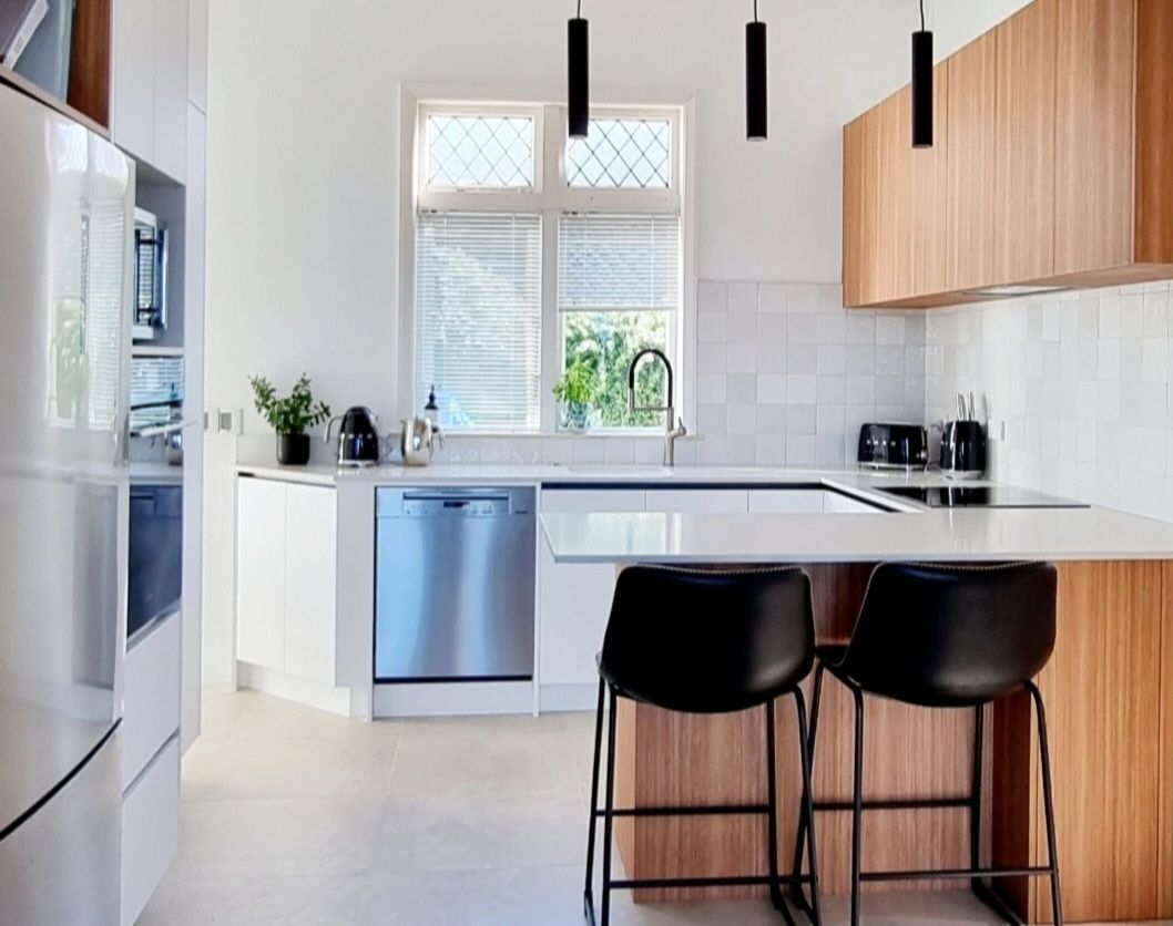 A kitchen with white cabinets , stainless steel appliances , a sink , and a window.